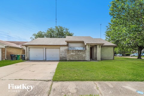 a brick house with a garage and a green lawn