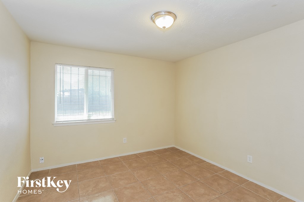 the living room of a home with a tiled floor and a window