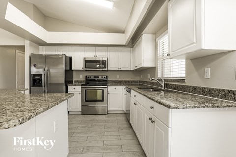 a kitchen with white cabinets and granite counter tops and stainless steel appliances