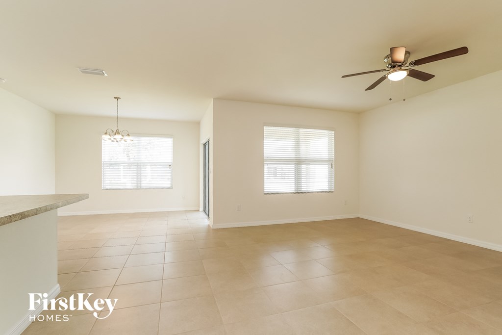 A spacious room with a ceiling fan and two windows.