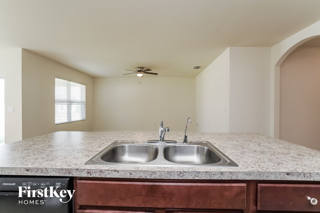 A kitchen with a granite countertop and a stainless steel sink.