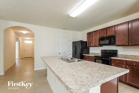 A kitchen with brown cabinets and a black fridge.