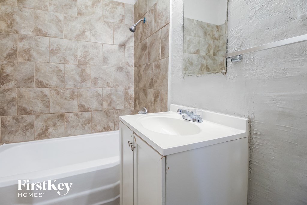 a bathroom with a sink and a tub and a mirror