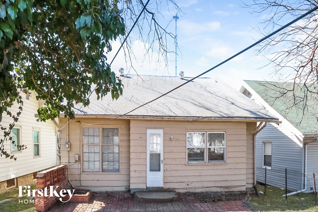 the front of a white house with a yard and a tree