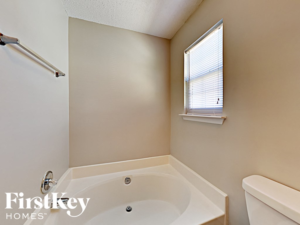 a bathroom with a tub and a toilet and a window