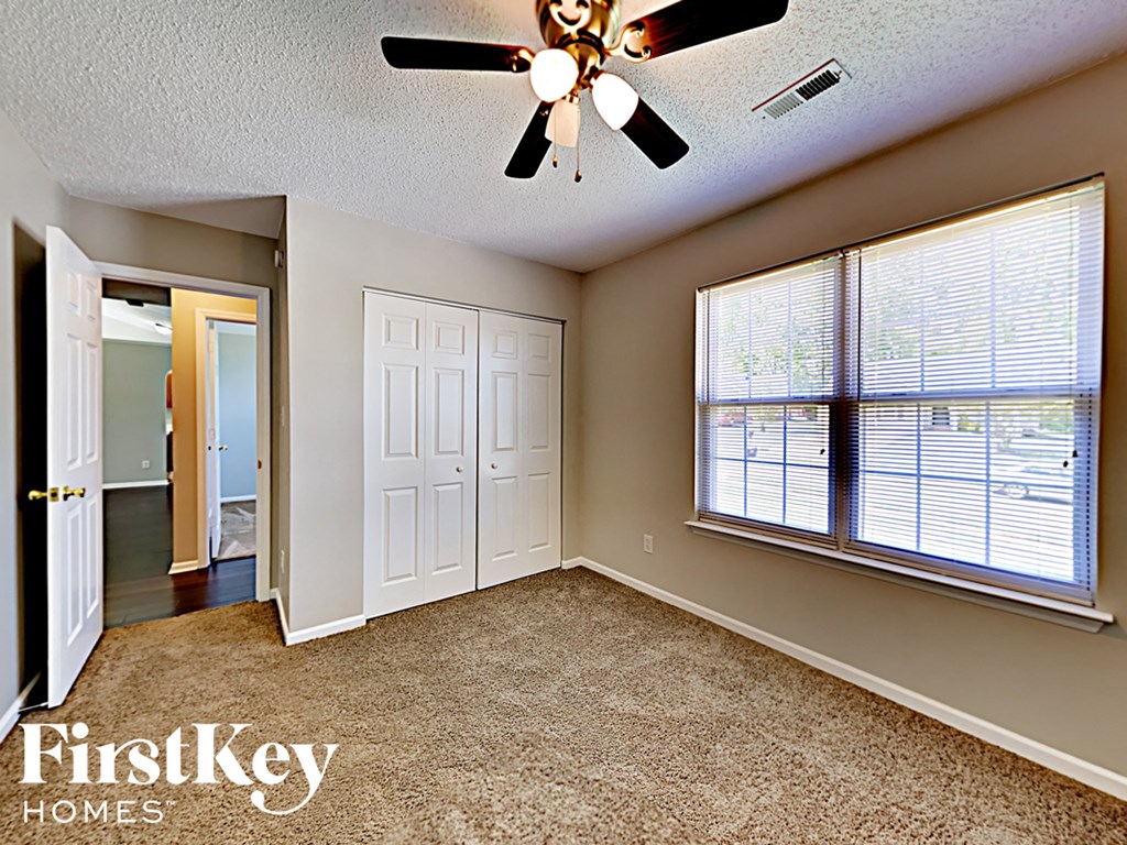 an empty bedroom with a ceiling fan and a window