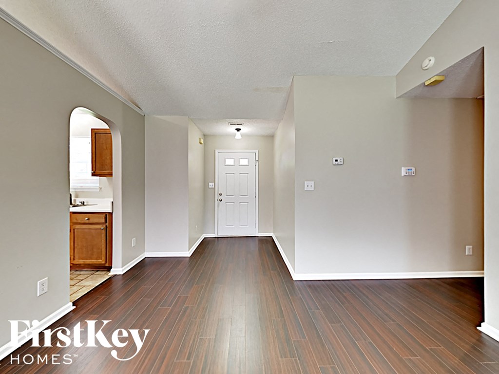 an empty living room with wood flooring and a white door