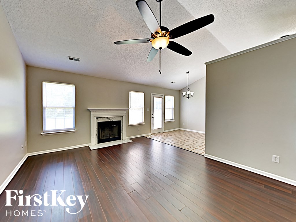 an empty living room with a ceiling fan and a fireplace