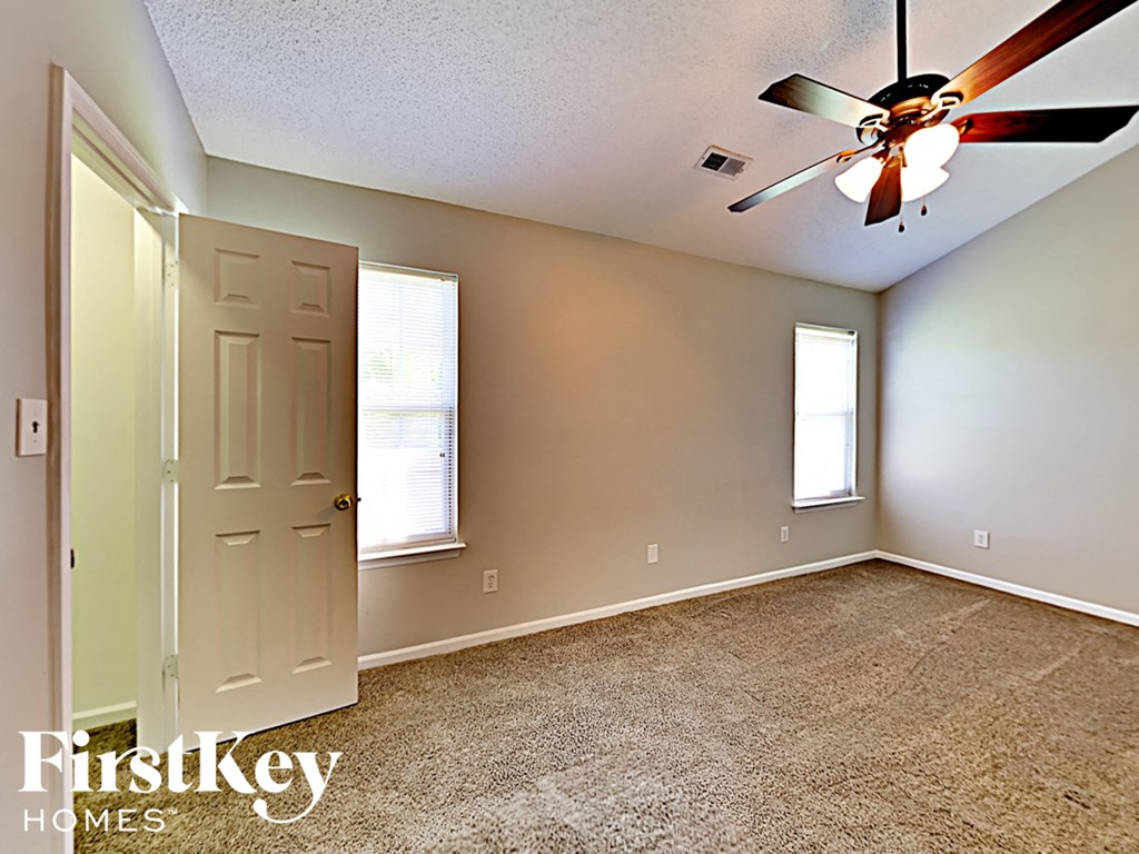 the bonus room has a ceiling fan and a door