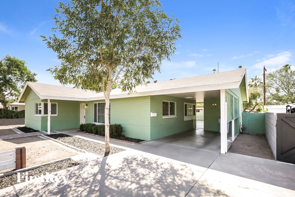 a green house with a tree in front of it