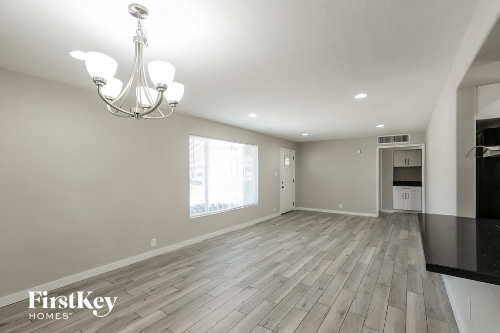 an empty living room with hardwood floors and a chandelier