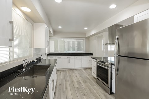 a white kitchen with black counter tops and stainless steel appliances