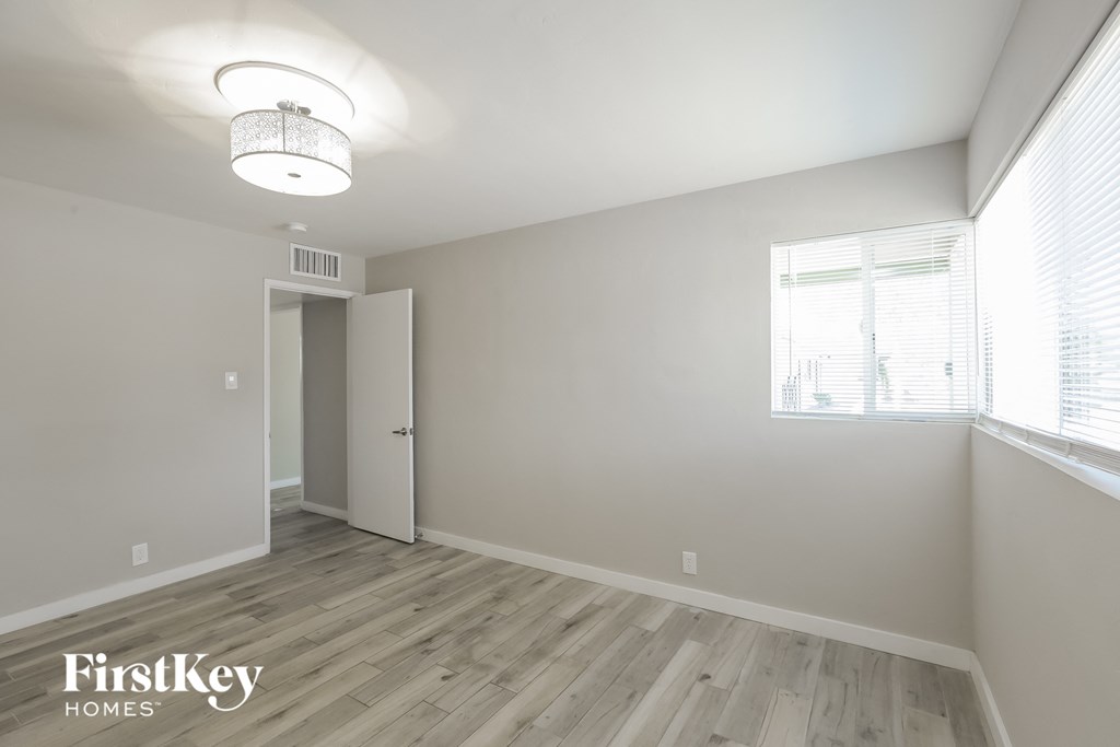 a bedroom with white walls and wood flooring and a window