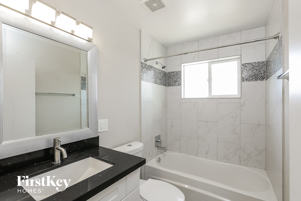 a white bathroom with a tub and a sink and a mirror