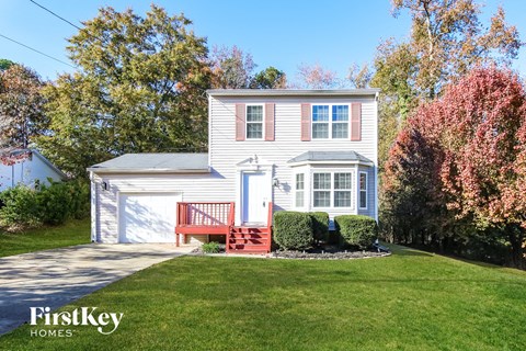 a white house with a red front porch and a lawn