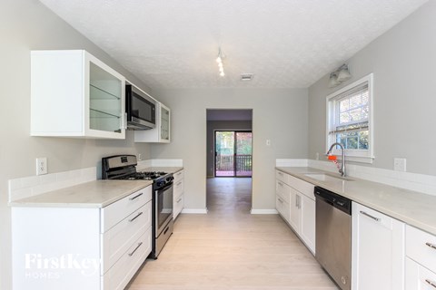 an empty kitchen with white cabinets and stainless steel appliances