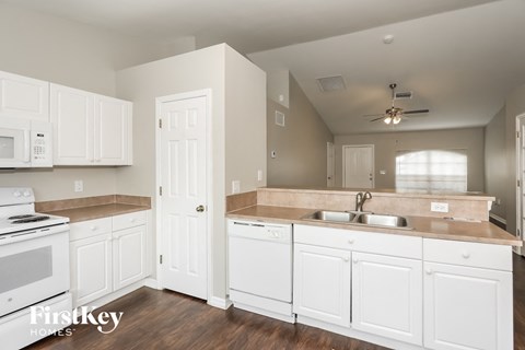 A kitchen with white cabinets and a stove top oven.