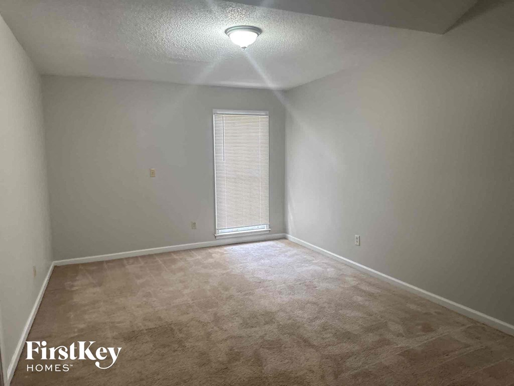 a bedroom with a large window and a carpeted floor