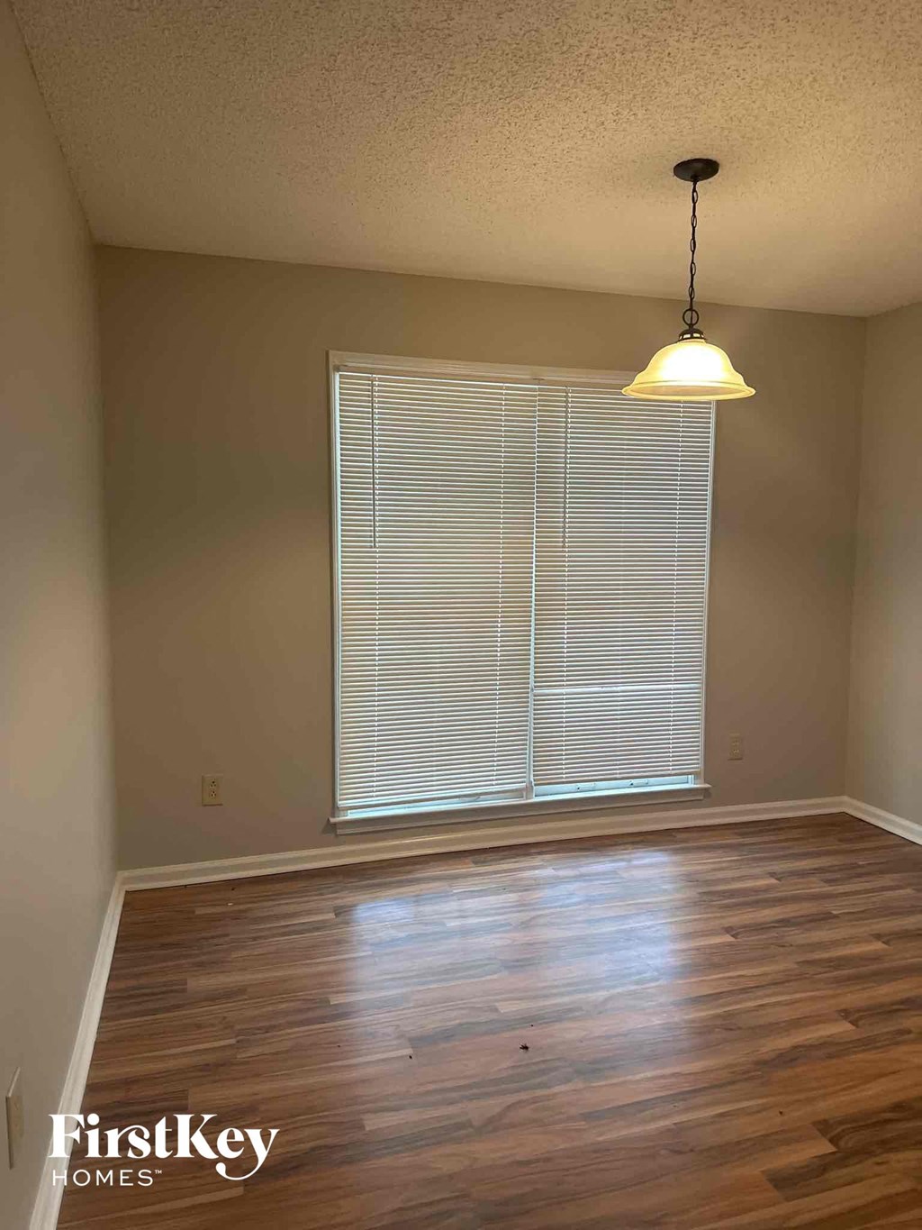 an empty living room with wood floors and a large window