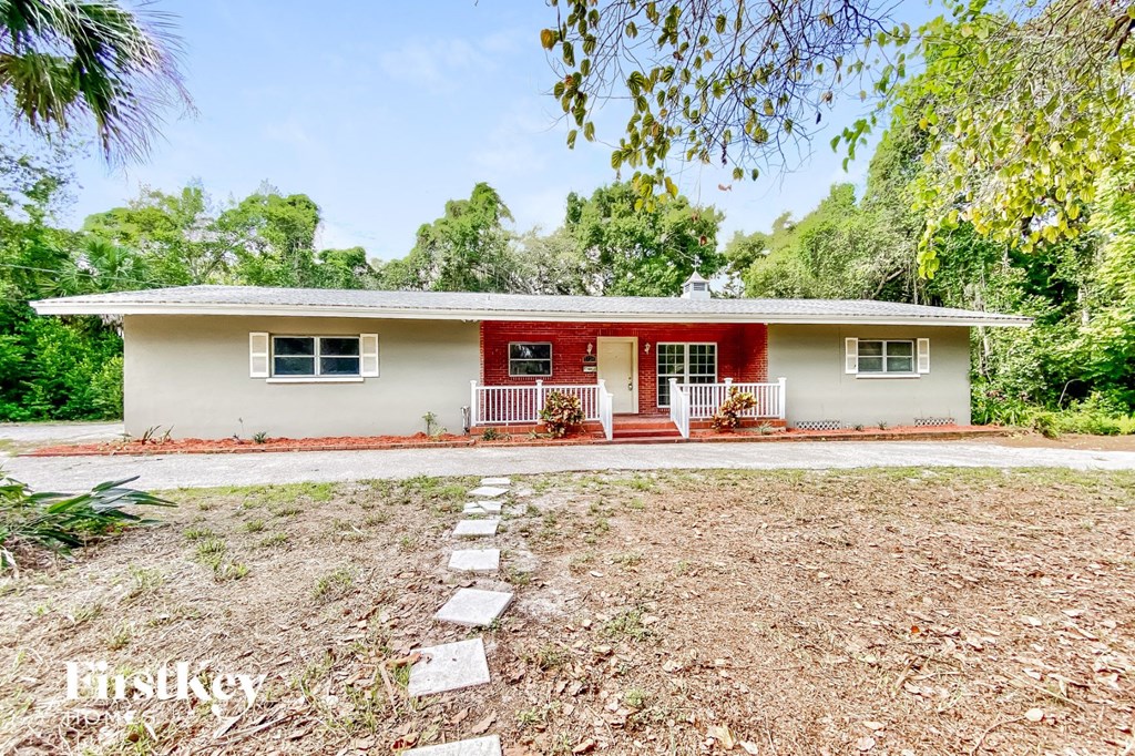 a small white house with a yard and trees