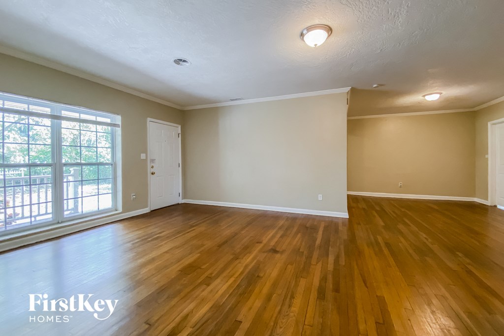 the living room of an empty house with wood floors and a window