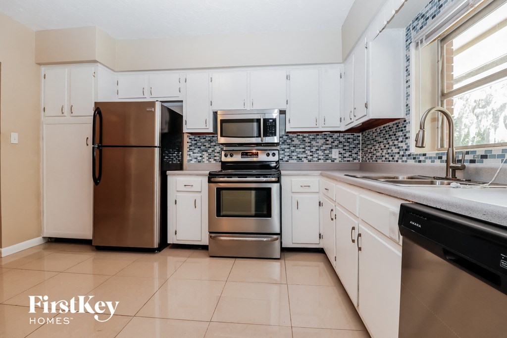 a kitchen with white cabinets and stainless steel appliances