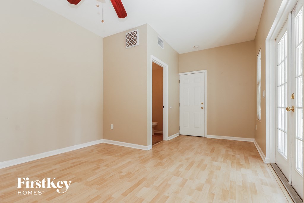 the living room of an empty house with wood floors and a white door
