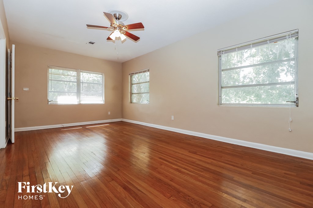 an empty living room with wood floors and a ceiling fan