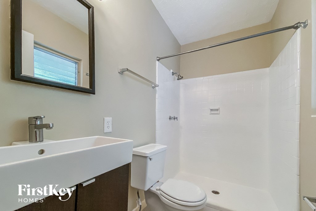 a bathroom with a shower toilet and sink and a mirror