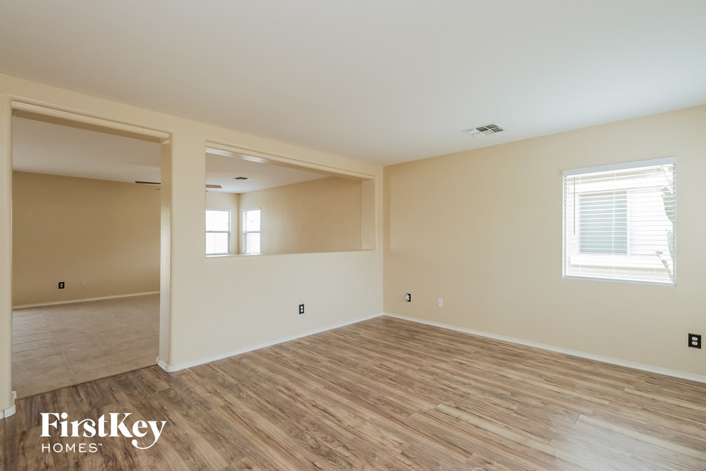 the spacious living room with wood flooring and white walls