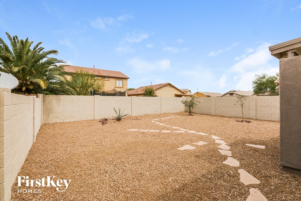 a pathway leading to the backyard of a house with palm trees