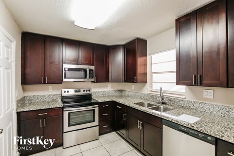 A kitchen with dark brown cabinets and a granite countertop.