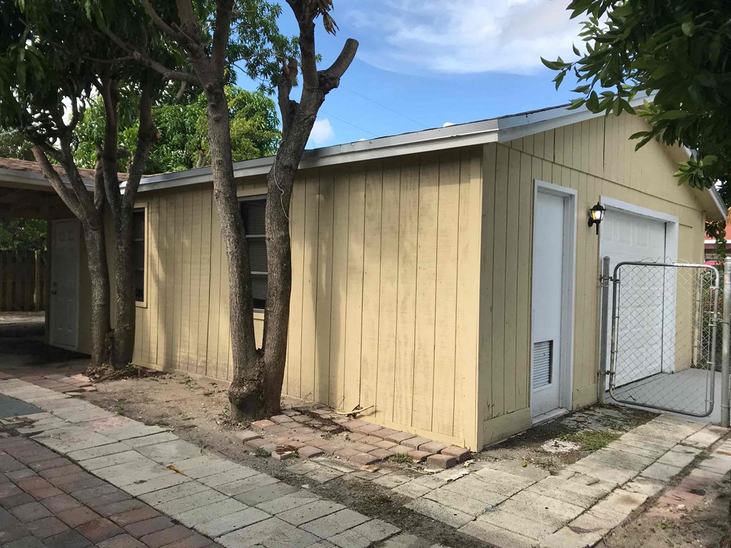 A small wooden building with a white door and a gate.