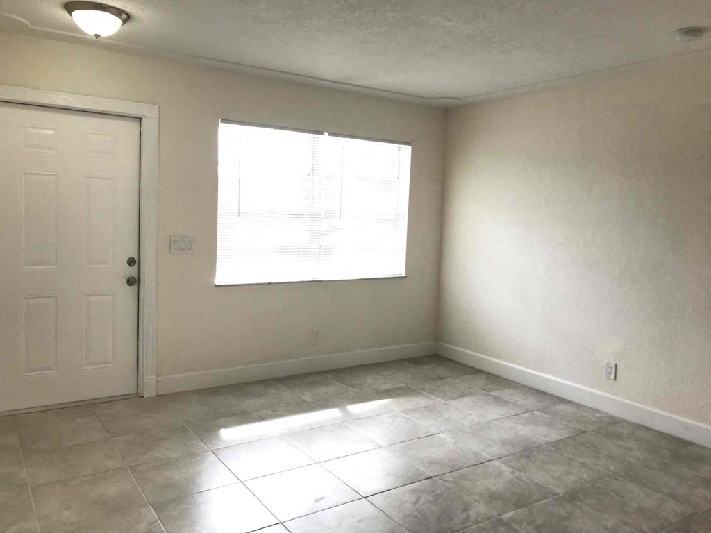 A room with a white door and a window with sunlight coming through.
