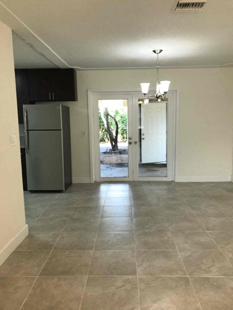 A kitchen with a refrigerator and a door leading outside.