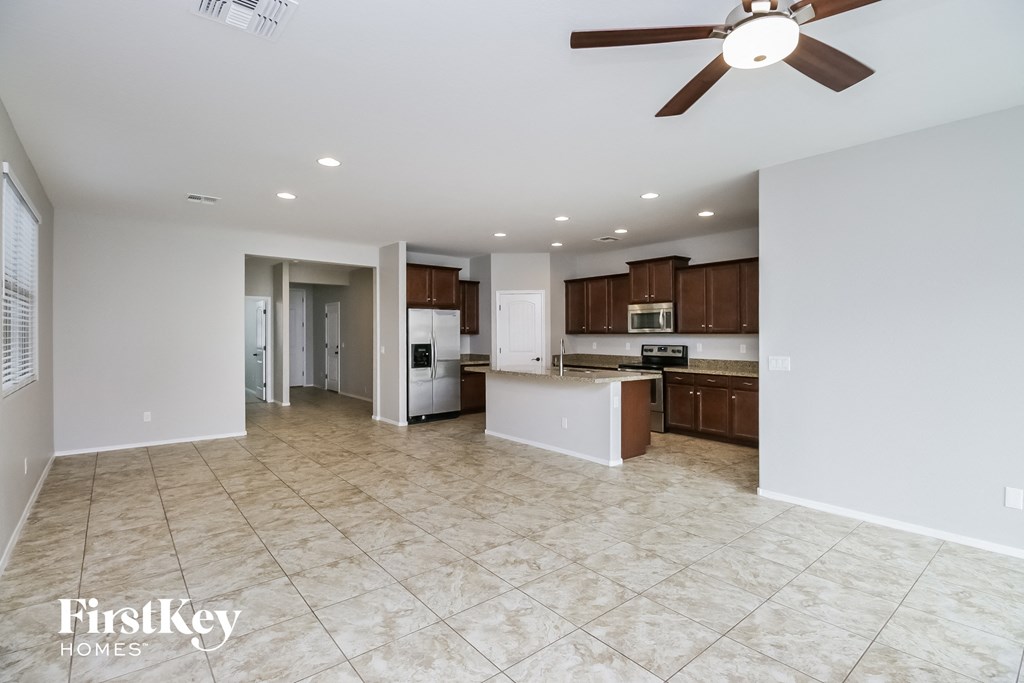 A spacious kitchen and living room with a ceiling fan and tiled flooring.