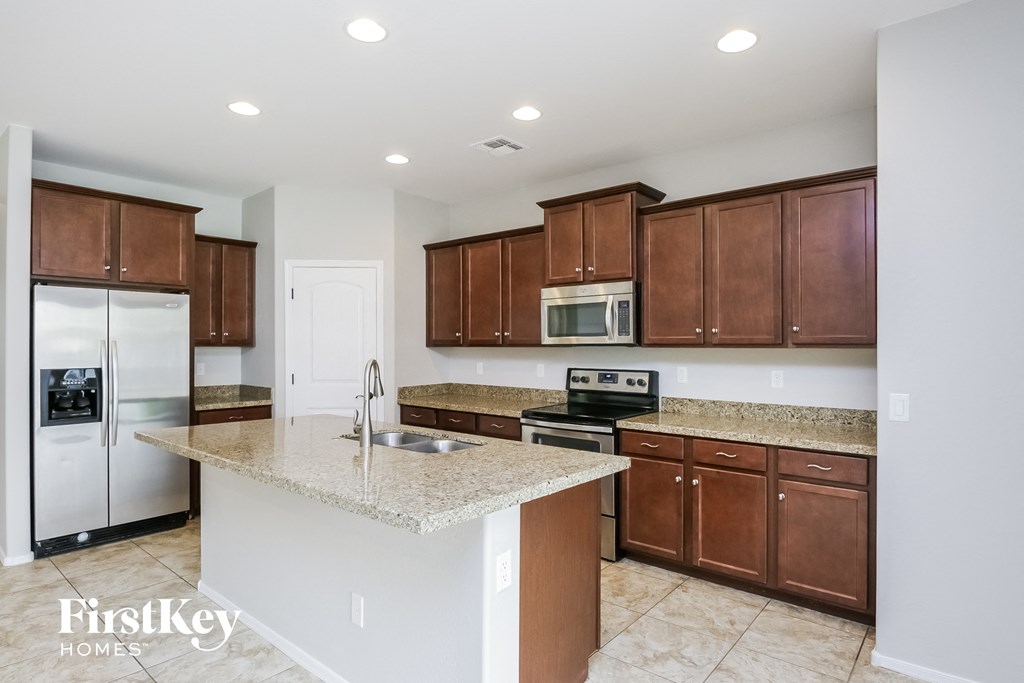 A kitchen with brown cabinets and a marble countertop.