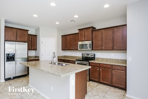A kitchen with brown cabinets and a marble countertop.