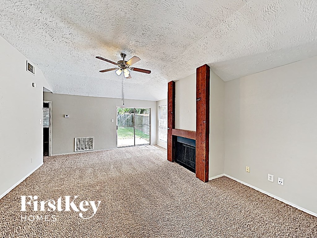 an empty living room with a ceiling fan and a fireplace