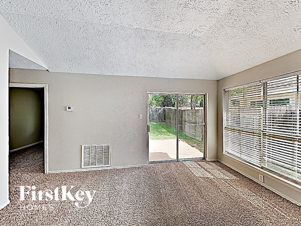 an empty living room with a sliding glass door to a yard