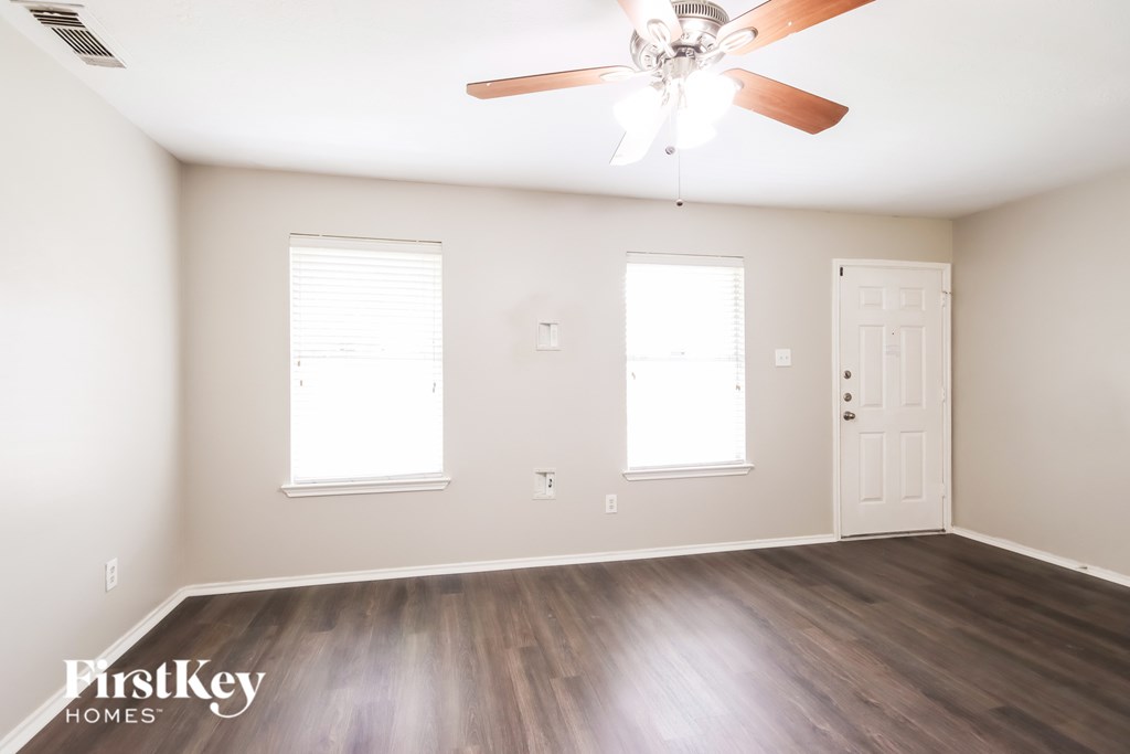 A room with a ceiling fan and wooden flooring.