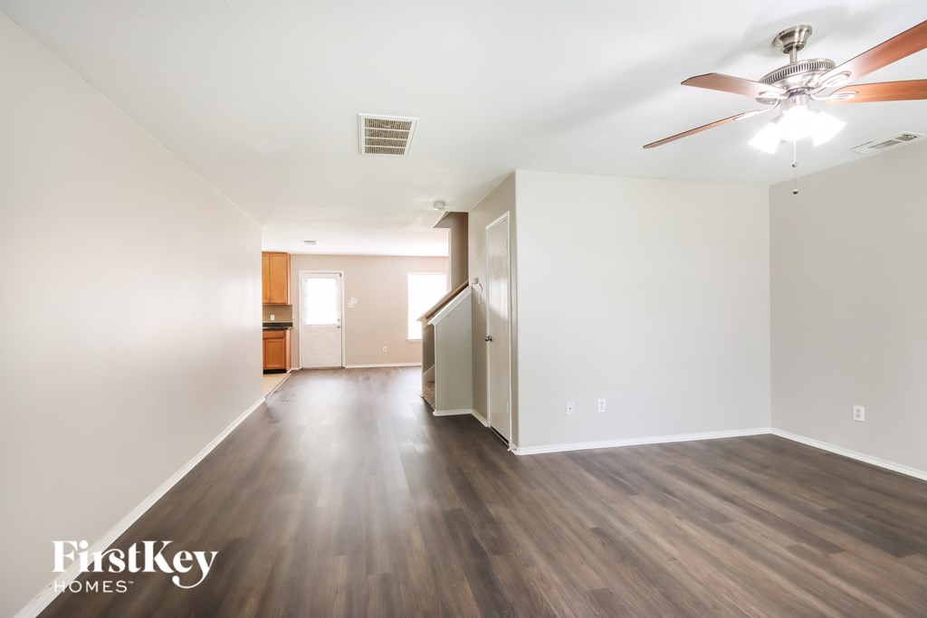 A room with a ceiling fan and wooden flooring.