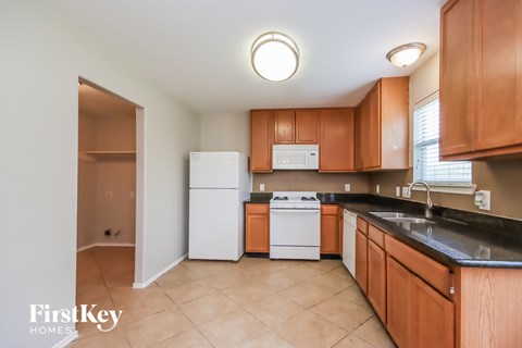 A kitchen with brown cabinets and a white fridge.