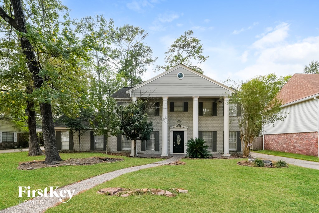 A house with a porch and a tree in front of it.