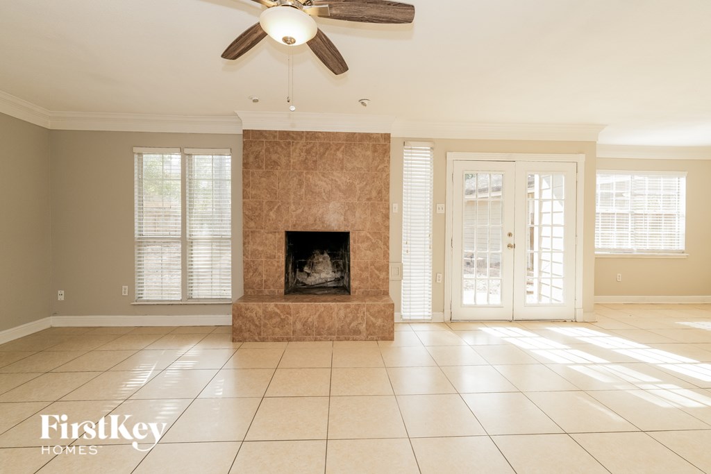 A living room with a fireplace and a ceiling fan.