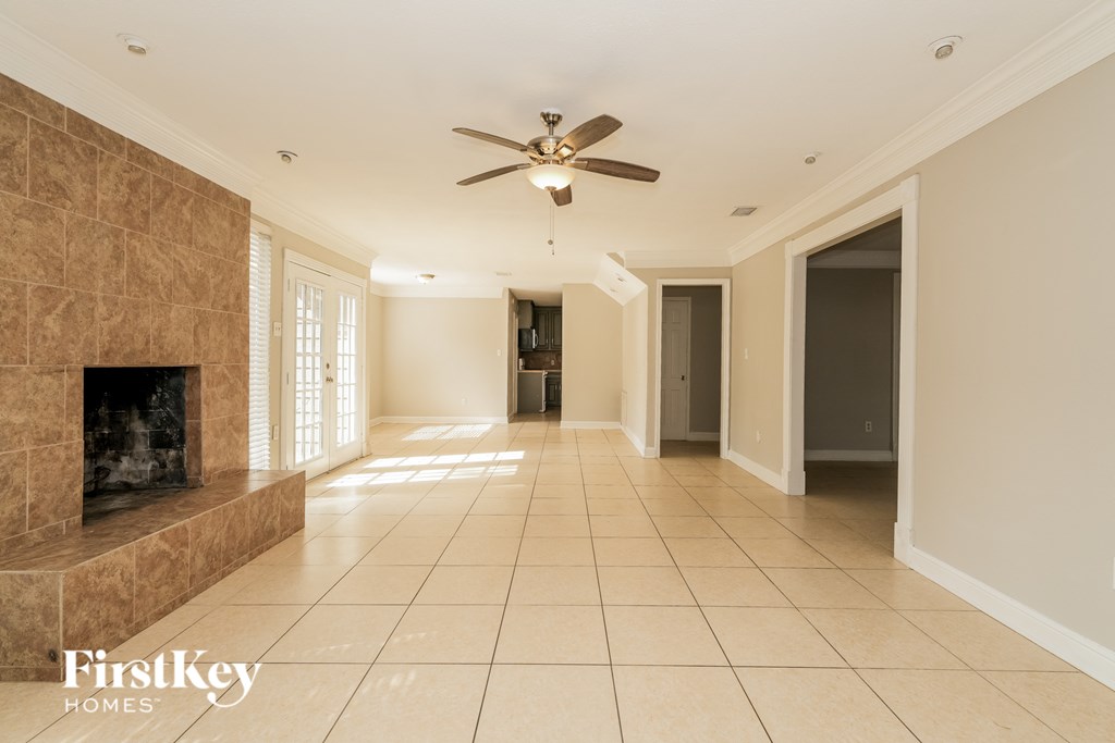 A spacious room with a fireplace and a ceiling fan.