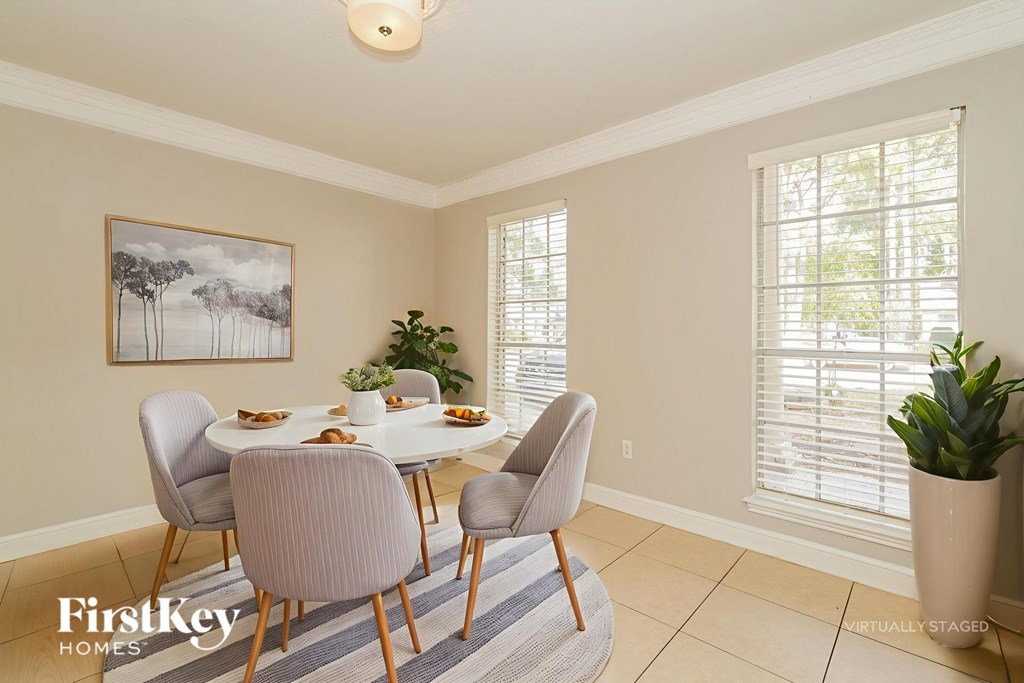 A dining room with a table set for six and a painting on the wall.