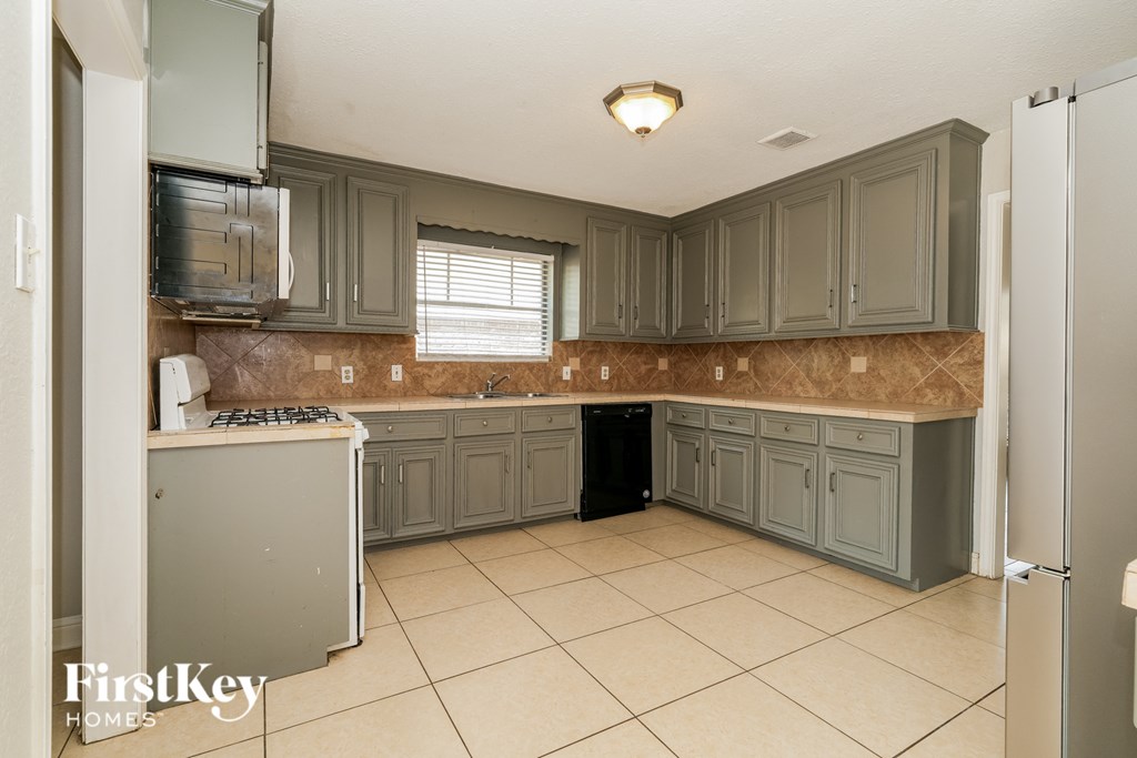A kitchen with a refrigerator, microwave, and oven.