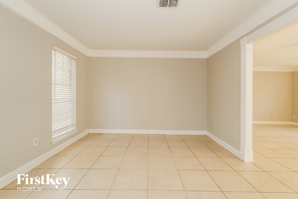 A room with a tile floor and a window with blinds.