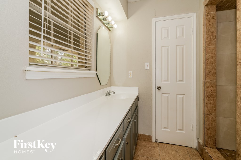 A white door is in a bathroom with a white sink.